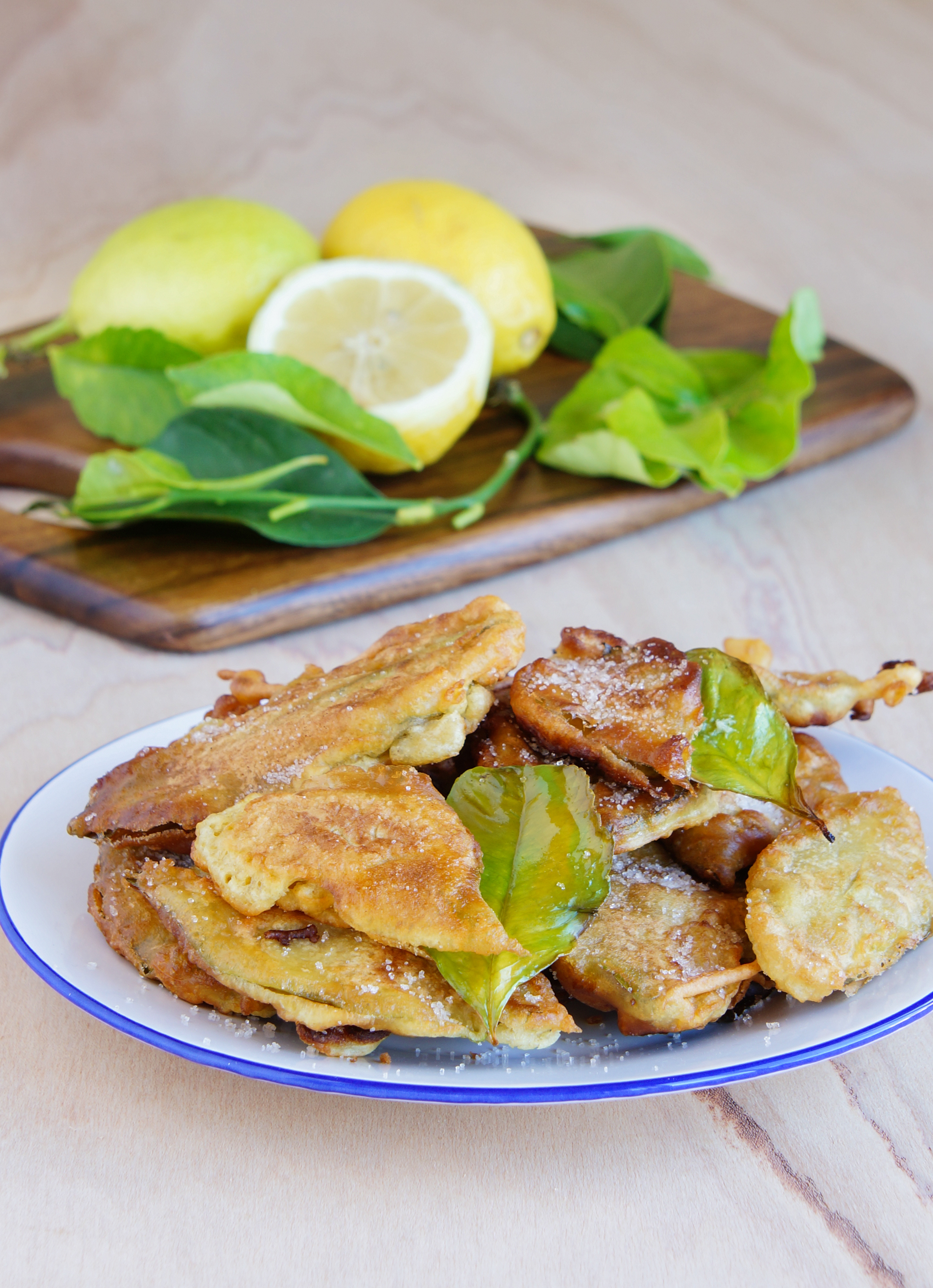 A plate of paparajotes, Murcia&rsquo;s traditional fried lemon-leaf dessert, served with fresh lemons and leaves in the background.